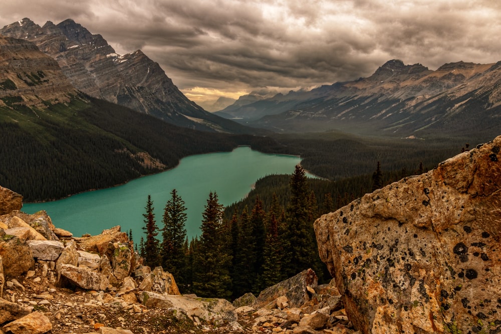 a view of a lake and mountains from a rocky cliff