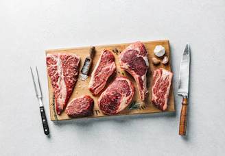 a cutting board with raw meat and a knife