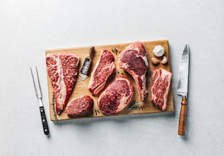 a cutting board with raw meat and a knife