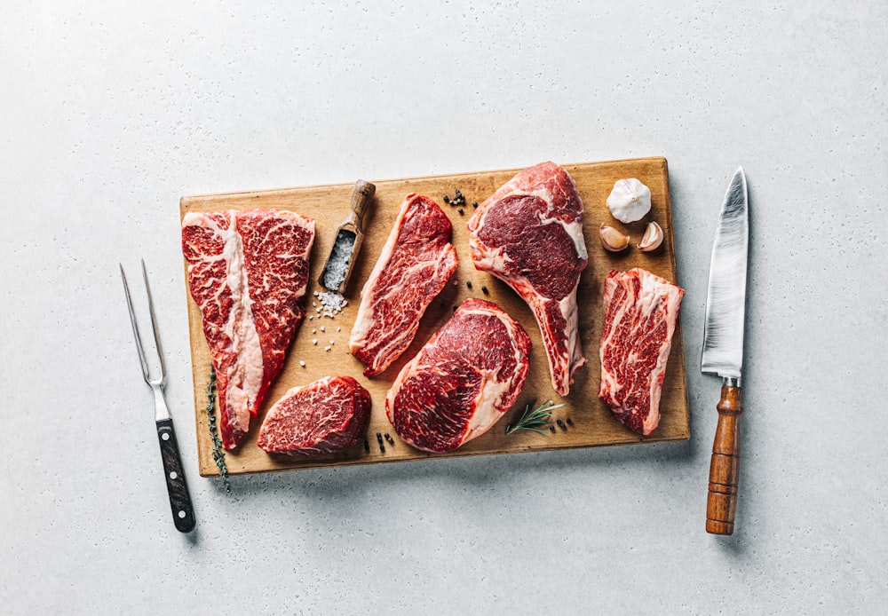 a cutting board with raw meat and a knife