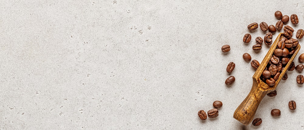 a wooden spoon filled with coffee beans on top of a table