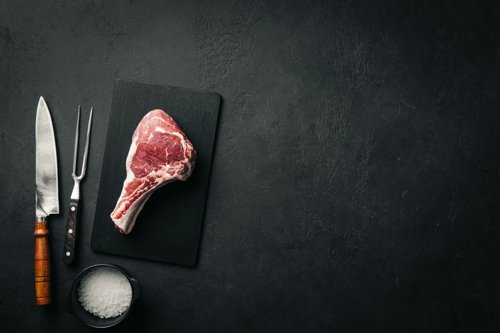 a piece of meat sitting on top of a cutting board next to a knife