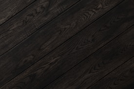 Dark wood planks with visible grain patterns and subtle variations in tone create a sleek and elegant texture.