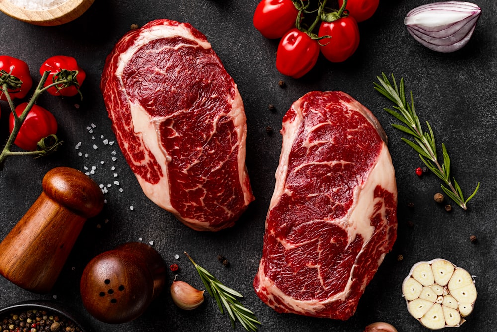 a couple of steaks sitting on top of a table