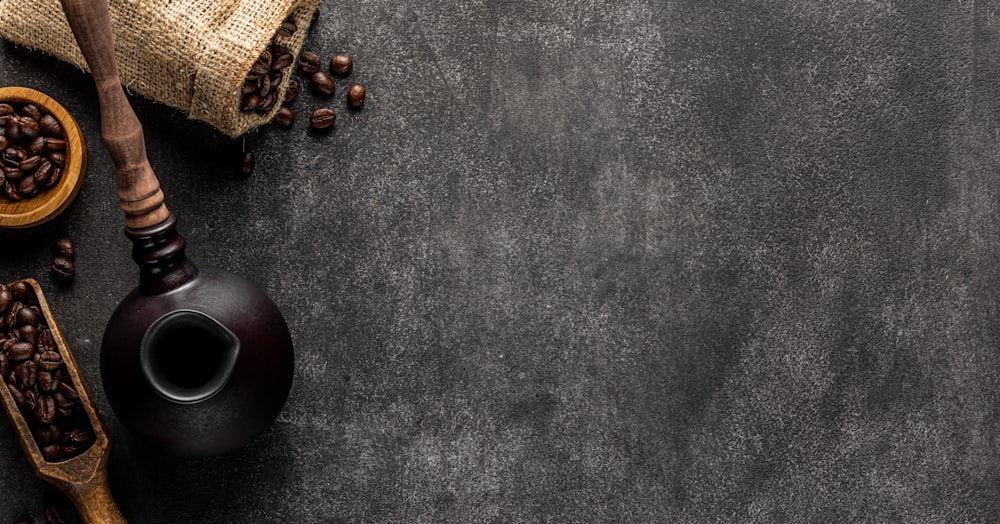 a black table with coffee beans and a wooden spoon