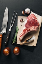 a piece of meat sitting on top of a cutting board next to a knife