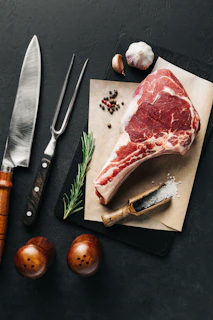 a piece of meat sitting on top of a cutting board next to a knife