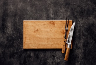 a wooden cutting board with a knife and fork