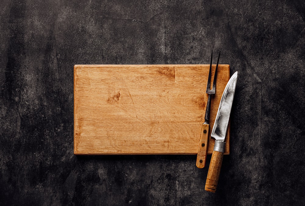 a wooden cutting board with a knife and fork