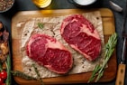 two steaks on a cutting board with herbs and spices