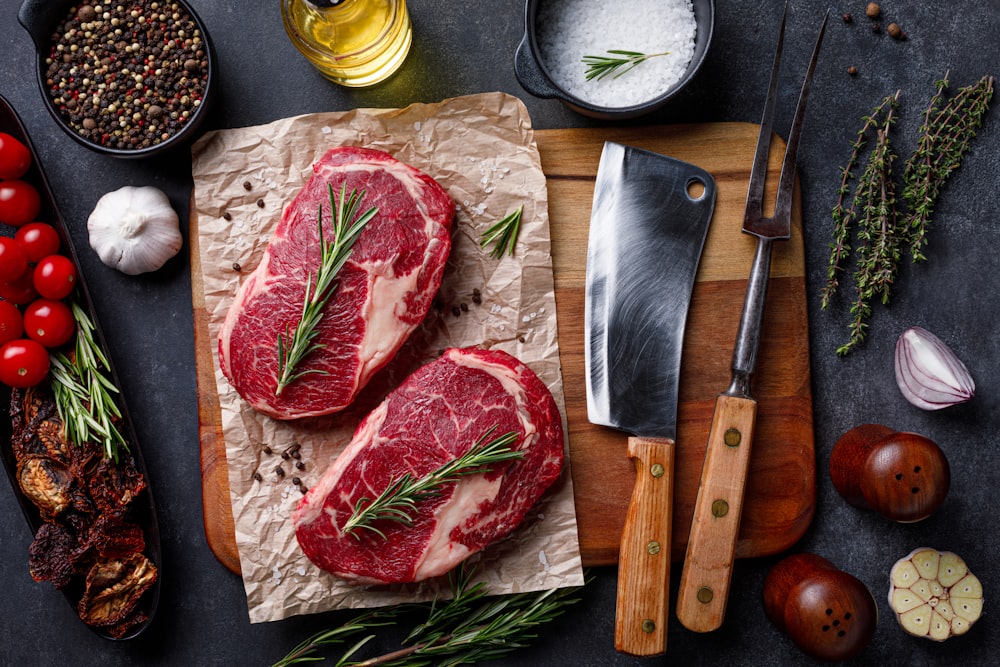 a cutting board topped with raw meat next to a knife