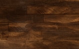 Dark wooden planks arranged horizontally with a textured surface, displaying a rich brown tone with subtle variations and natural grain patterns.