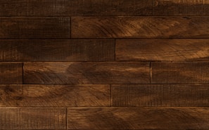 Dark wooden planks arranged horizontally with a textured surface, displaying a rich brown tone with subtle variations and natural grain patterns.
