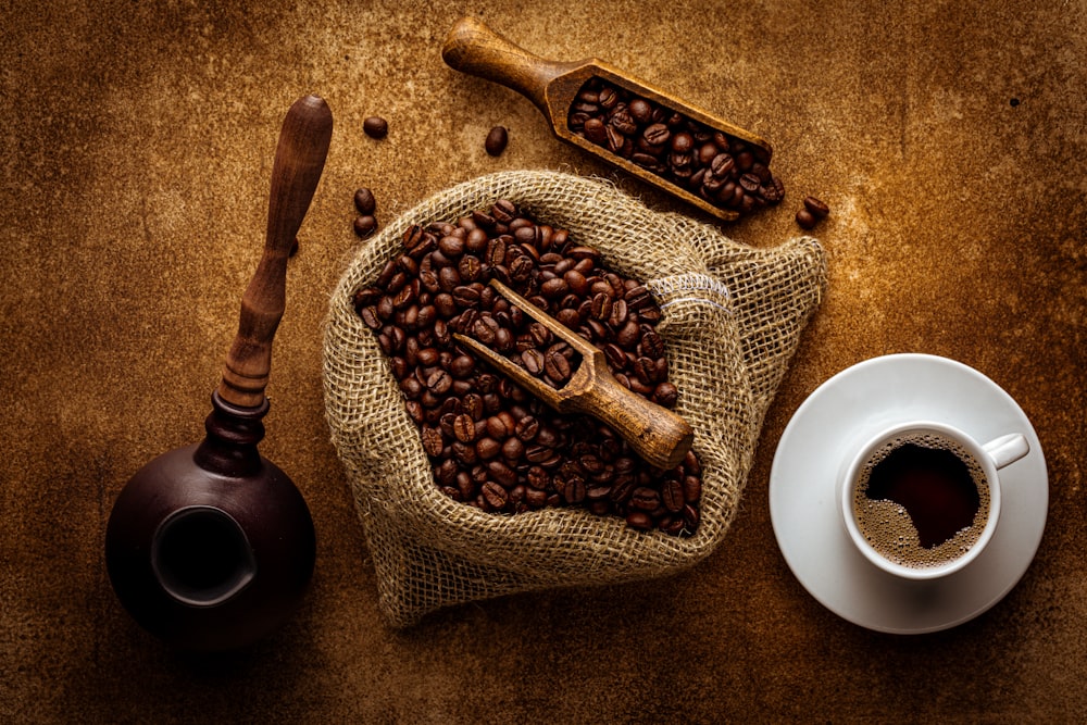 a sack of coffee beans next to a cup of coffee