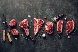Close-up of fresh, hand-cut beef steaks displayed on rustic wooden board with herbs.