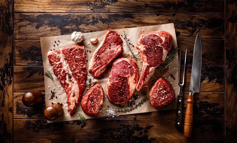 raw meat on a cutting board next to a knife