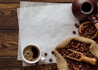 a cup of coffee next to a sack of coffee beans