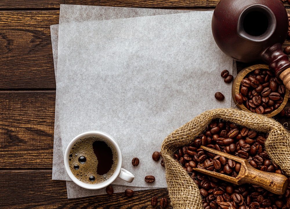 a cup of coffee next to a sack of coffee beans