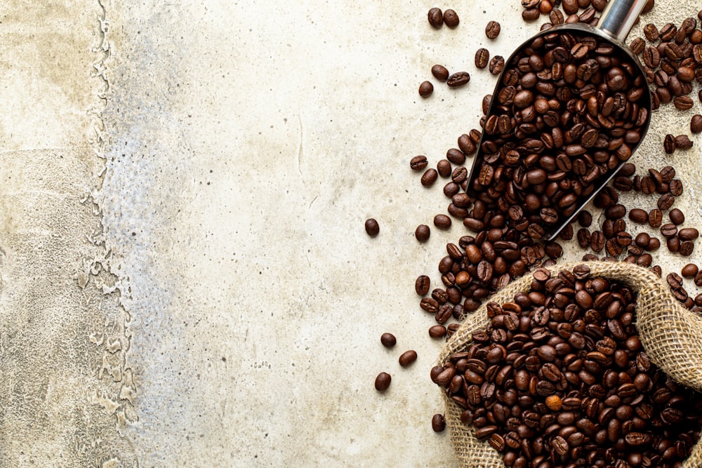 a scoop full of coffee beans next to a sack of coffee beans