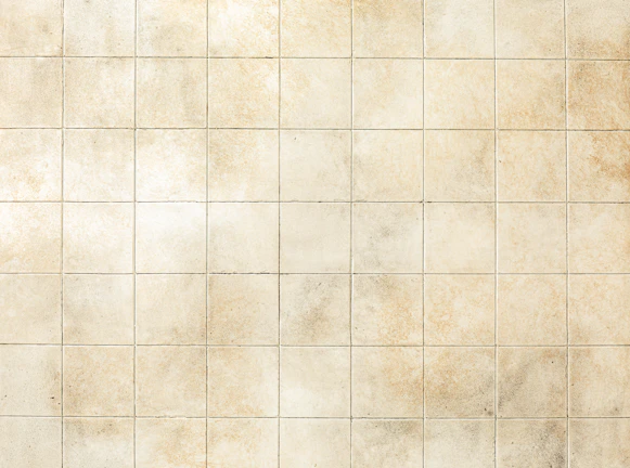 Close-up of elegant beige porcelain tiles with subtle texture under warm lighting.