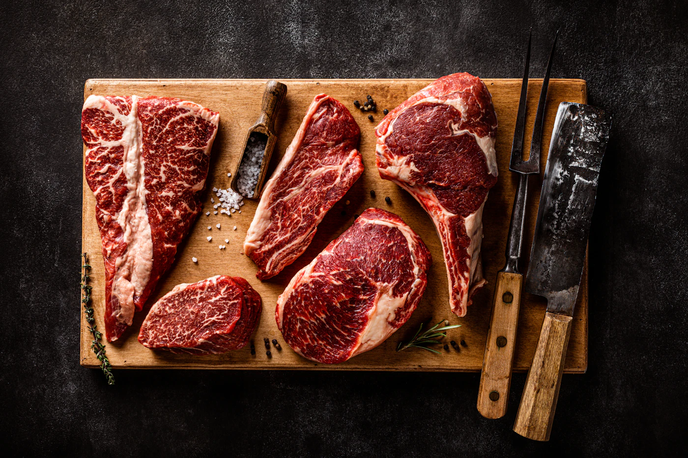 Mehrere Rindfleisch-Cuts auf einem Brett mit Messern