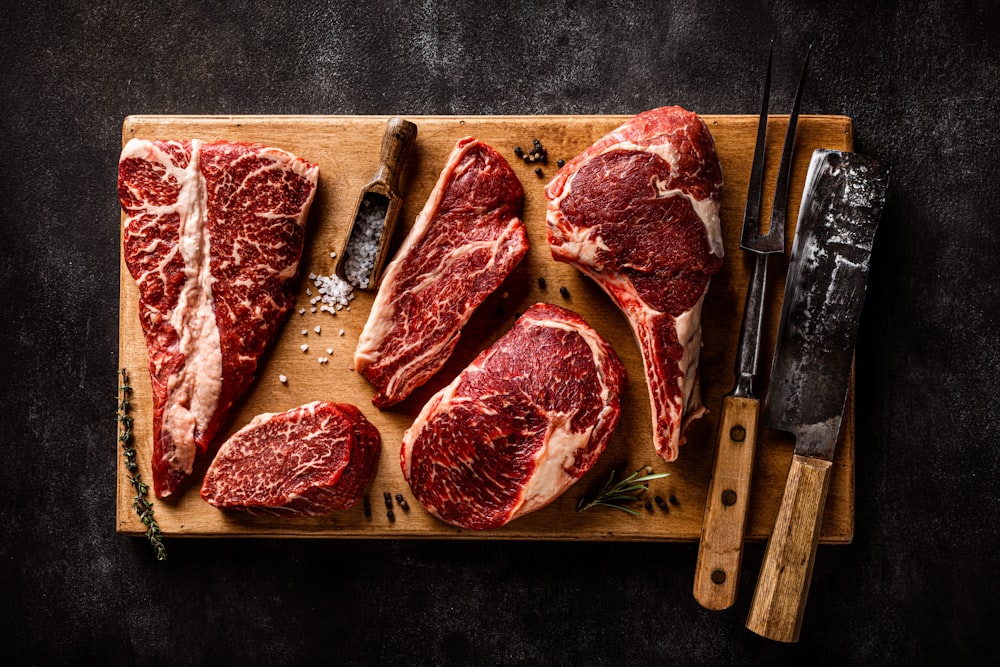 a cutting board with steaks and a knife on it