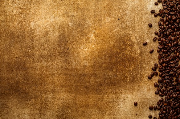A textured brown background covers most of the image with a collection of dark roasted coffee beans scattered along the right side. The beans are densely packed, creating a contrast between the smooth texture of the beans and the rougher, mottled surface of the background.