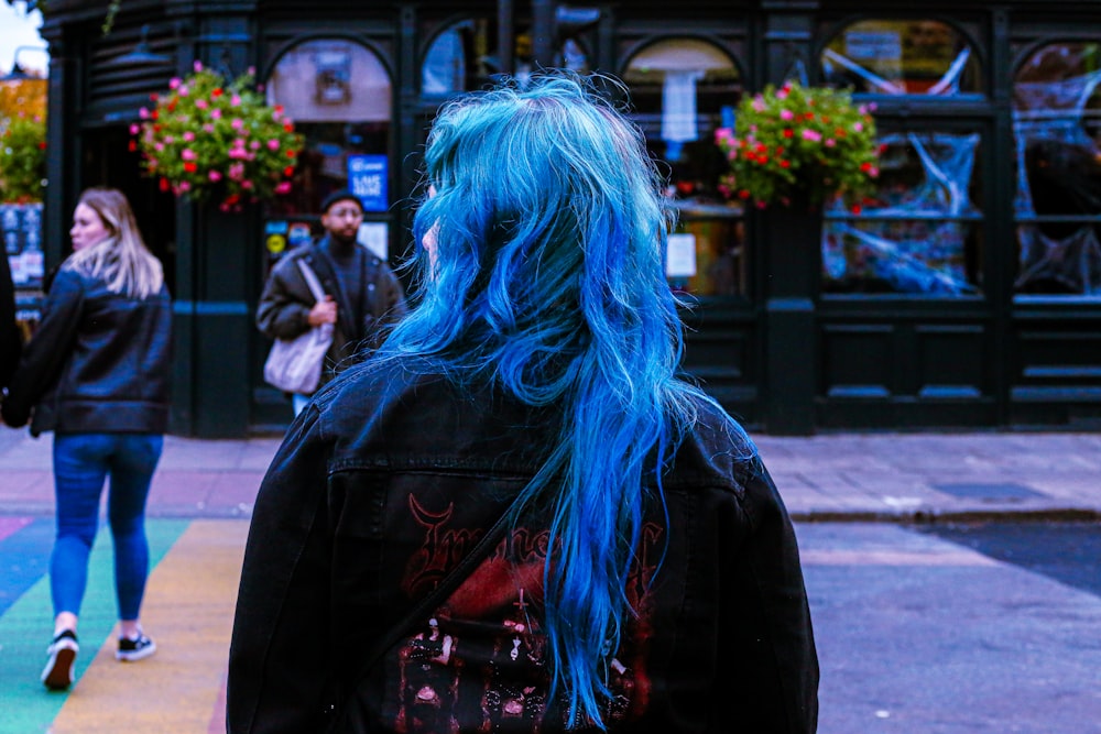 a woman with blue hair walking down the street