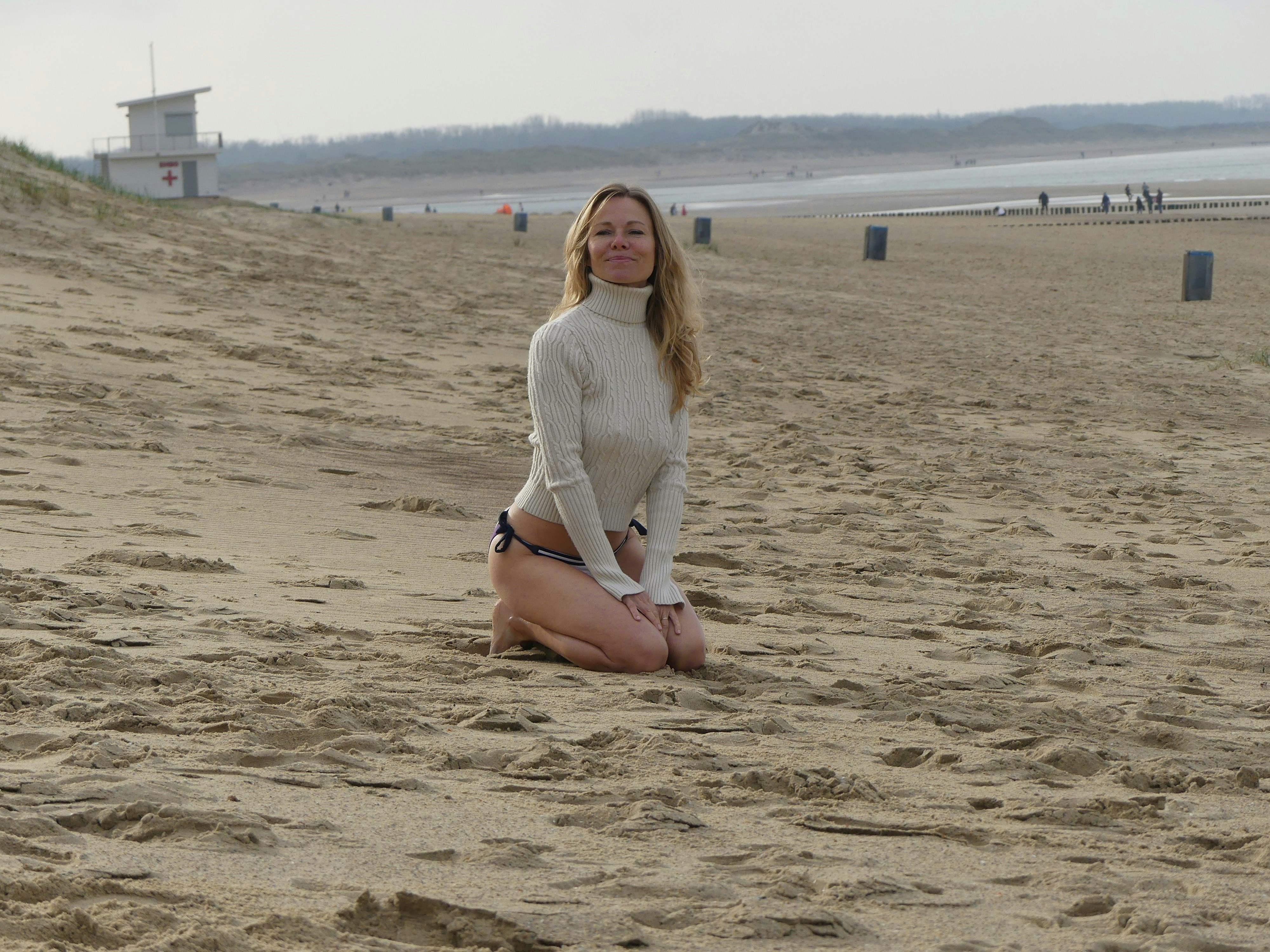 a woman sitting on a beach next to a frisbee