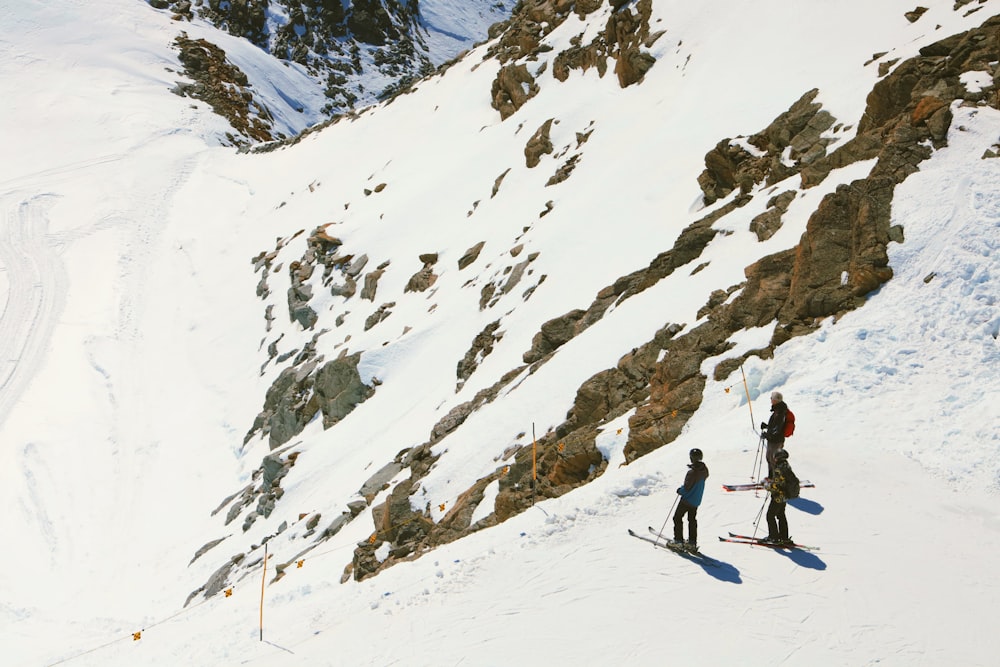 a couple of people riding skis down a snow covered slope