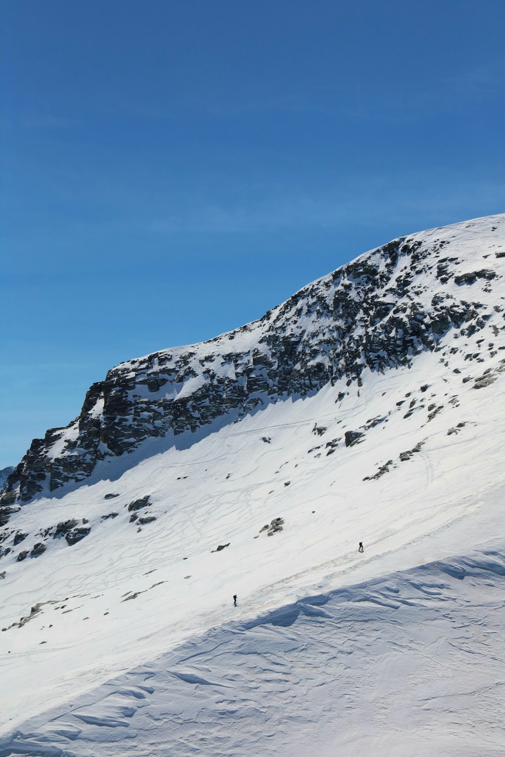 a snow covered mountain with people skiing down it