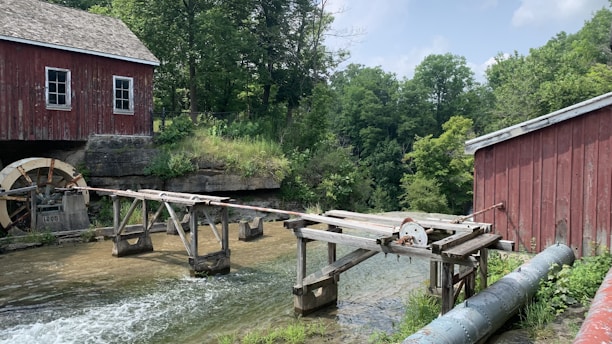 Historic water mill on a flowing stream surrounded by lush greenery.