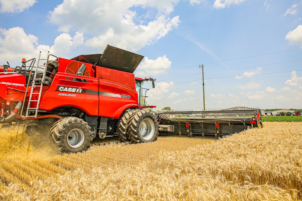 a red combine truck driving through a wheat field