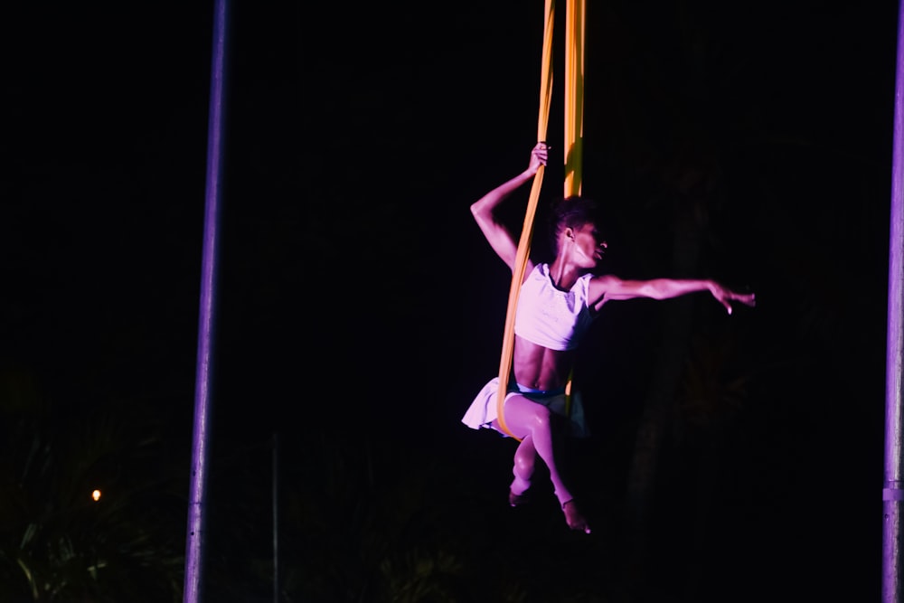 a woman hanging on to a pole in the dark