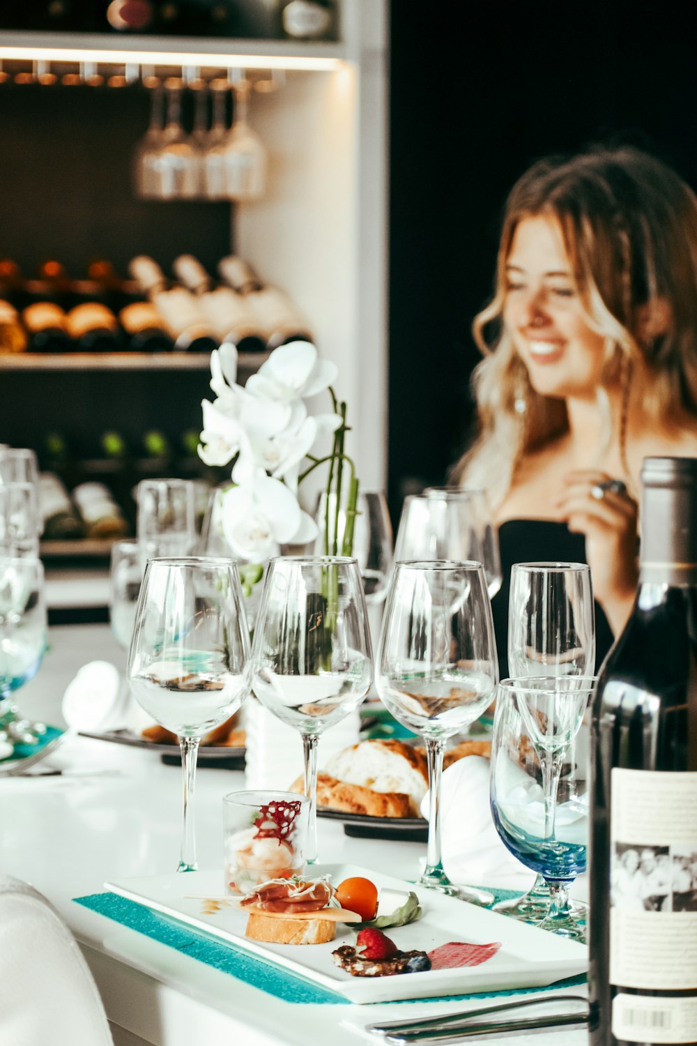 a woman sitting at a table with wine glasses