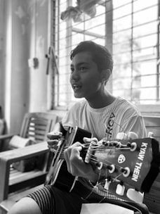 A beginner happily playing acoustic guitar in a cozy home setting.