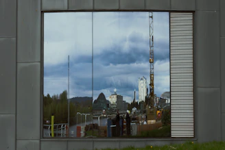 Close-up of a finely crafted aluminum window frame with reflective glass, capturing the city skyline.