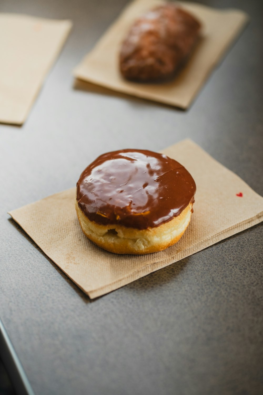 a chocolate covered doughnut sitting on top of a napkin