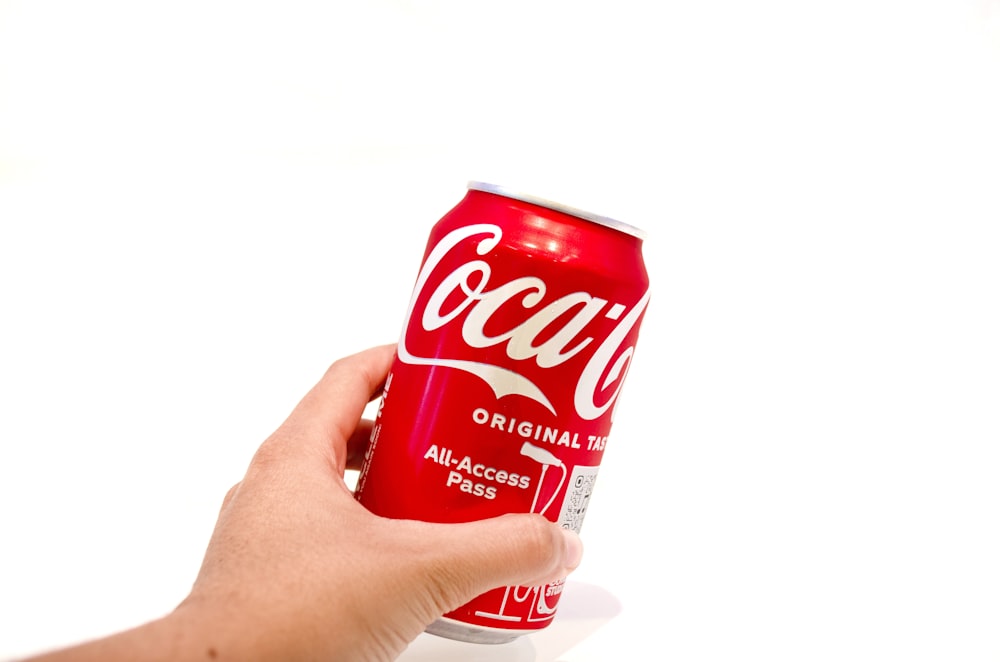 a hand holding a can of coca cola