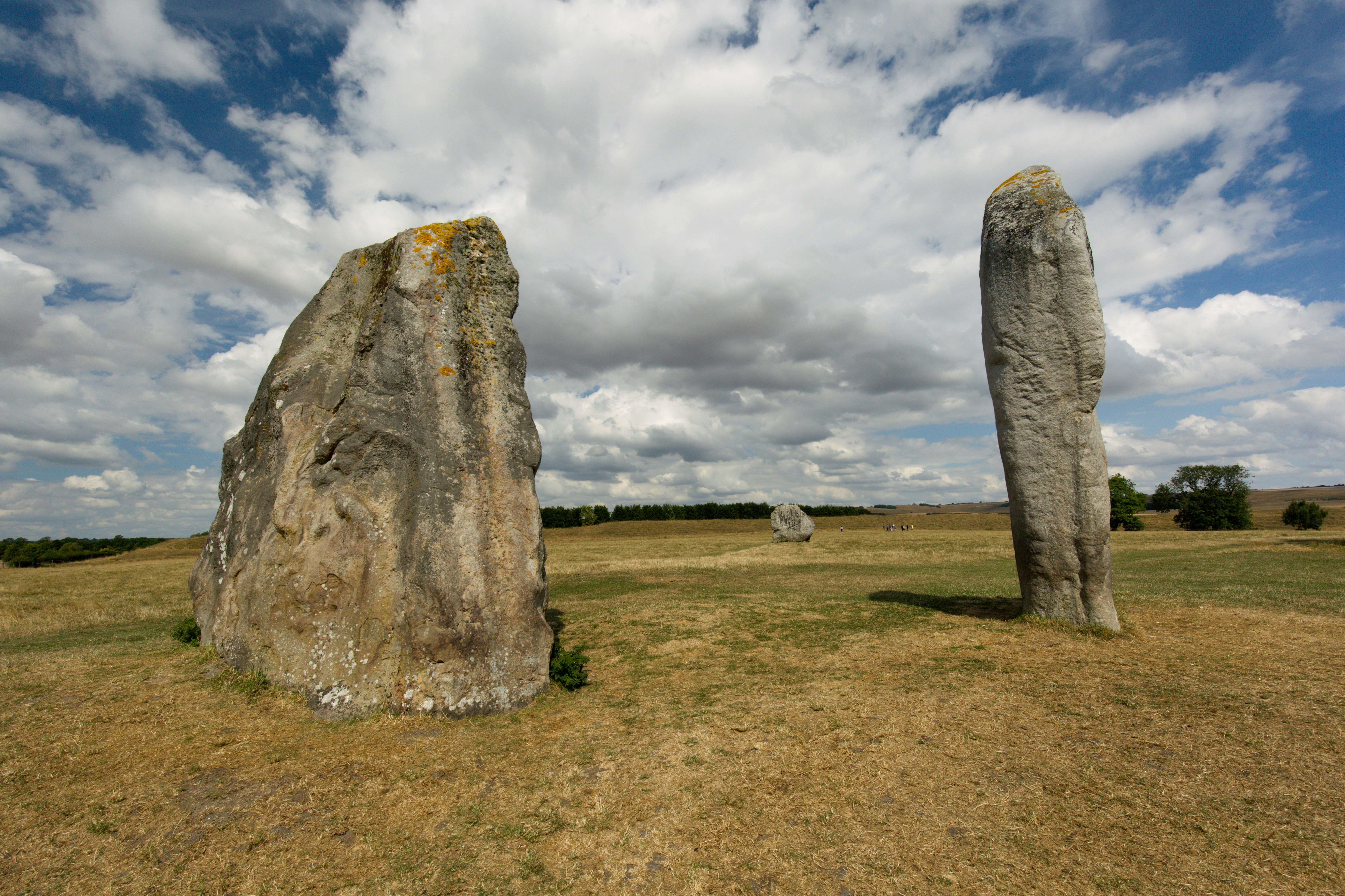 two large rocks in a grassy field under a cloudy sky