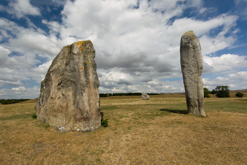 two large rocks in a grassy field under a cloudy sky