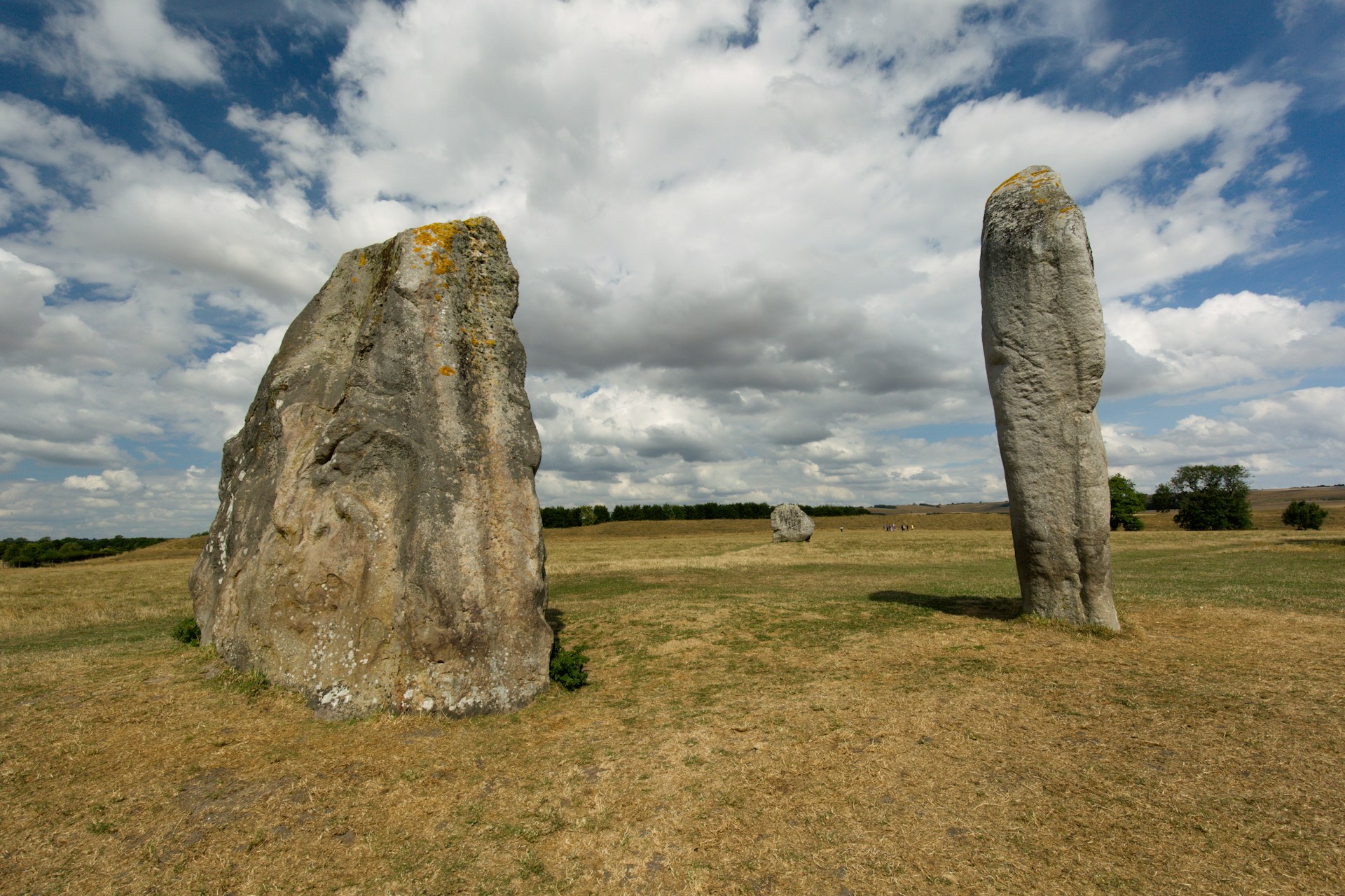 two large rocks in a grassy field under a cloudy sky