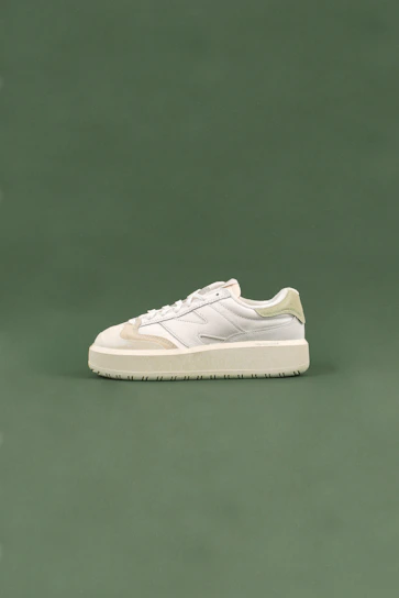 Soft pastel pink sneakers styled with delicate green olive accents on a cream background.