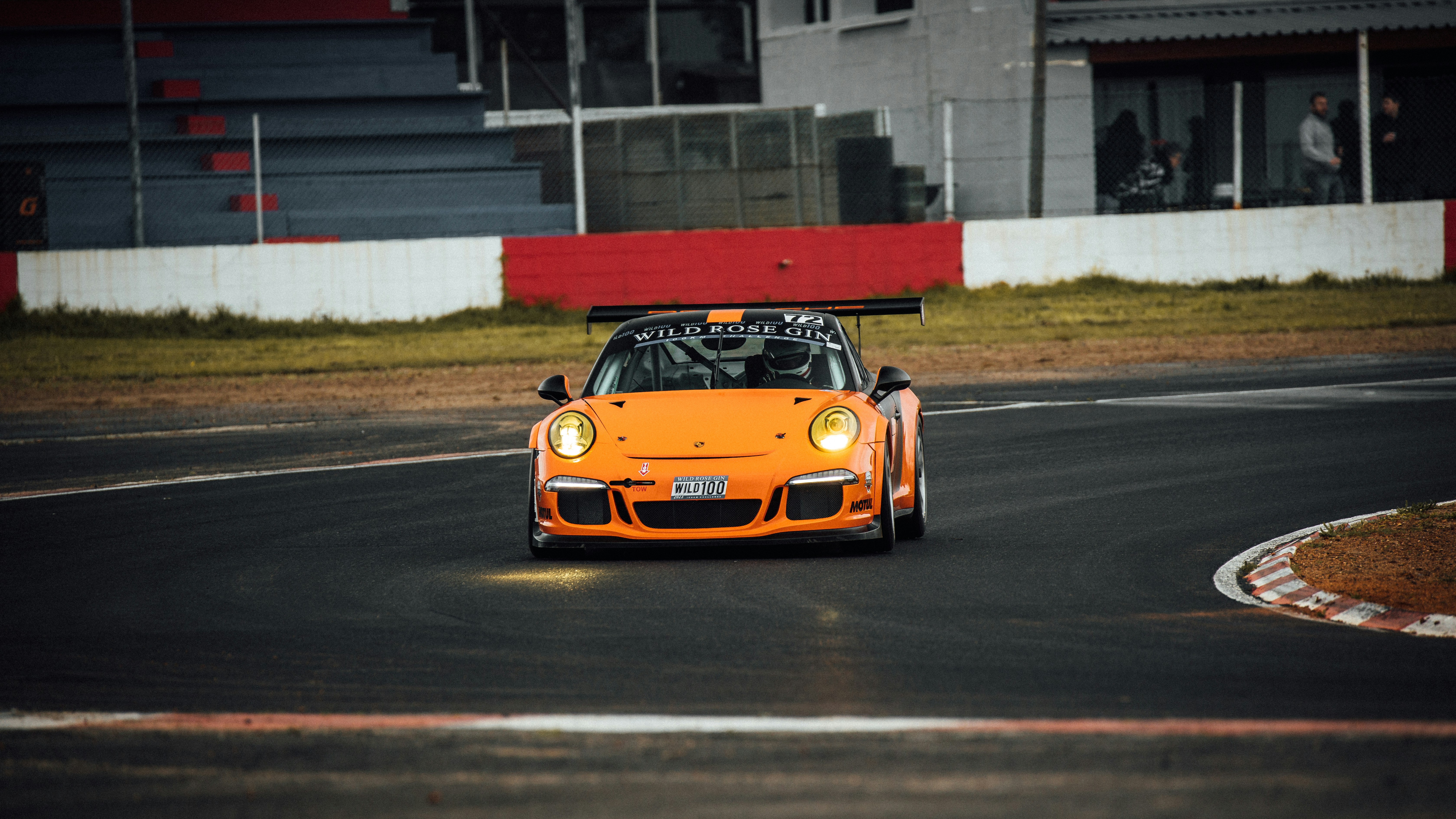 Un'auto sportiva arancione che guida su una pista da corsa