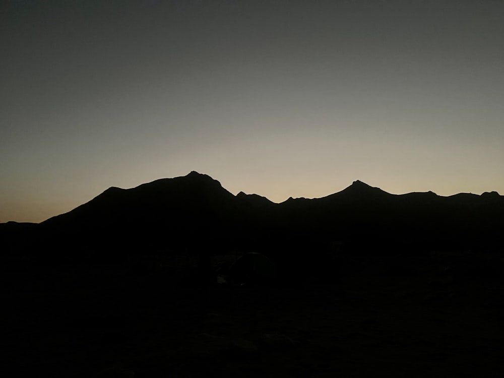 the silhouette of a mountain range against a dark sky