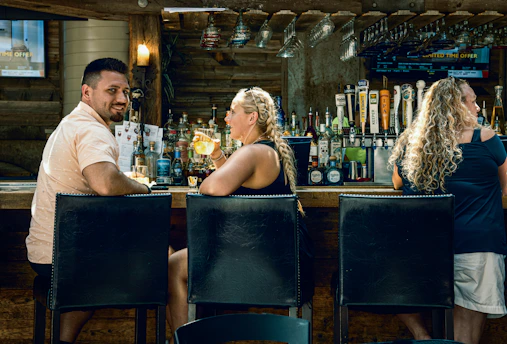 Friends laughing and enjoying drinks together in a warmly lit, inviting bar.