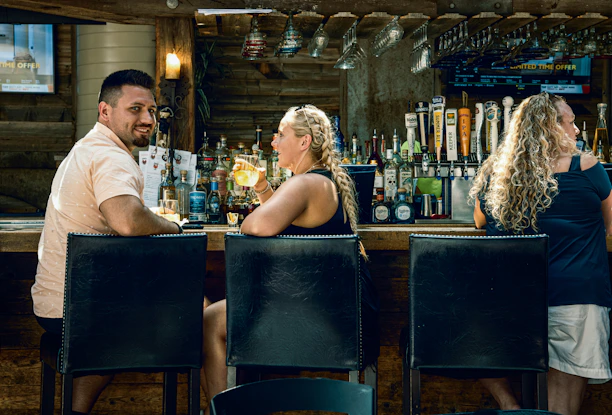 Cozy bar scene with friends enjoying colorful cocktails and lively conversation.