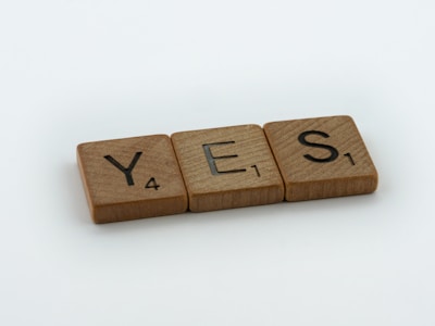 a wooden block spelling yes on a white background