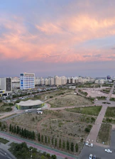 A sweeping aerial view of Central Park Flower Valley showcasing lush greenery, elegant architecture, and winding pathways under a soft golden light.