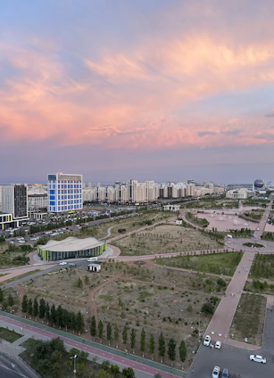A sweeping aerial view of Central Park Flower Valley showcasing lush greenery, elegant architecture, and winding pathways under a soft golden light.